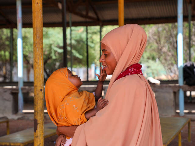 Damac lovingly stares at her baby at the health facility, grateful that she has fully recovered. After months of treatment for malnutrition, her child is now healthy, and Damac remains committed to ensuring her well-being.